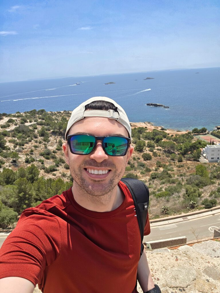 Bradley Rugg outdoors on a hillside overlooking the sea